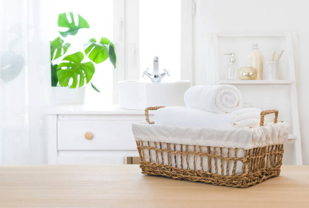Fluffy white Towels in wicker basket on table with bathroom windowsill background