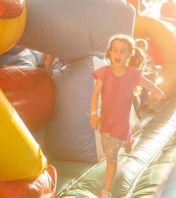 Happy little girl having lots of fun on a jumping castle during sliding