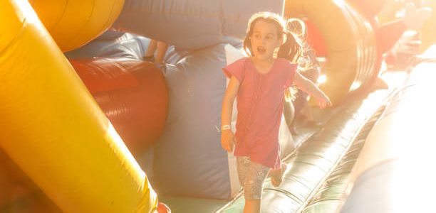 Happy little girl having lots of fun on a jumping castle during sliding