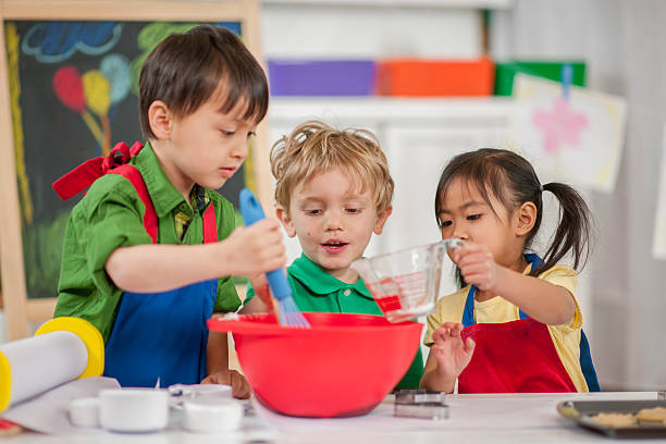 multi-ethnic group of kids baking cupcakes in cooking class