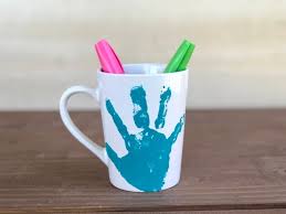 Blue handprint on mug with colourful pends inside it