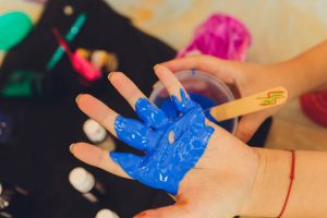 Blue paint of the hand of a baby ready to make a hand print on a mug