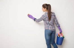 Woman wiping white with dry cloth, cleaning crayon marks on walls