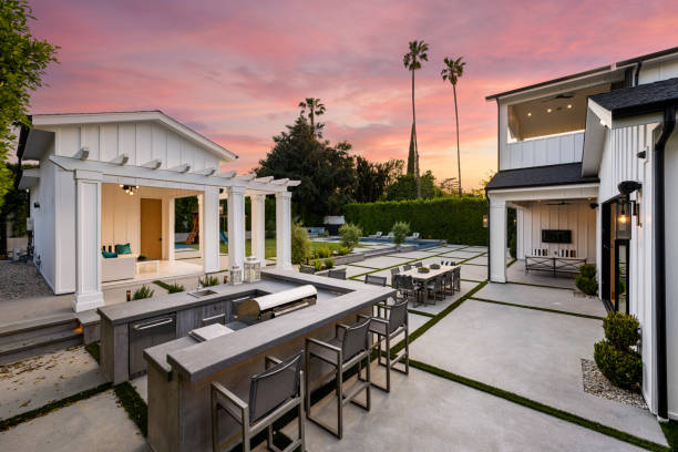 An outdoor kitchen with a fireplace, table, and chairs set in the evening light