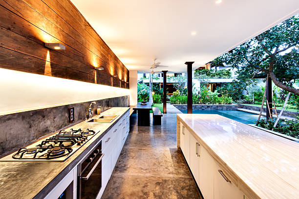 Outdoor kitchen with a stove an countertop next to garden including a pool