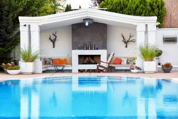 Backyard patio of a luxury residence with swimming pool and fireplace under diffuse daylight.