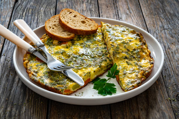 Frittata eggs with cheese and vegetables on wooden table