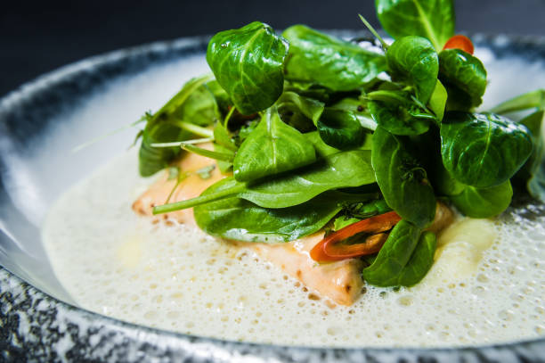 salmon steak under lettuce leaves, dark background, top view