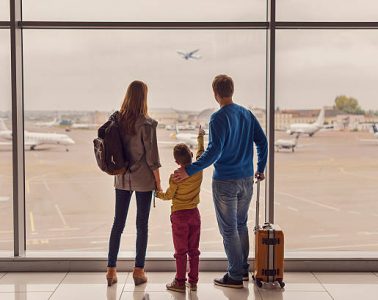 Such large aircraft. Back view shot of young family with luggage standing near window in airport before boarding