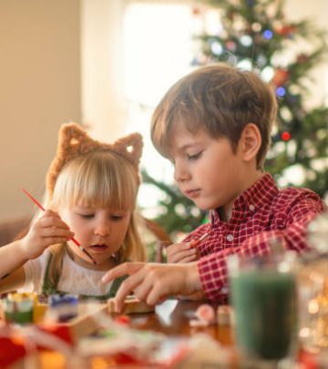 Children paint wooden toys near Christmas tree at home