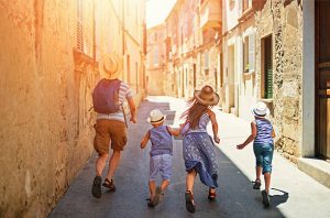 Father and kids running beautiful street of a mediterranean town. Sunny summer day. Pollenca, Mallorca, Spain.