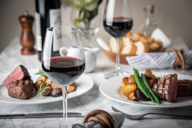 wine glasses on dining table with steak