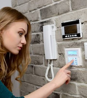 young blond woman activates an alarm in the house. Introduces a code using the keypad