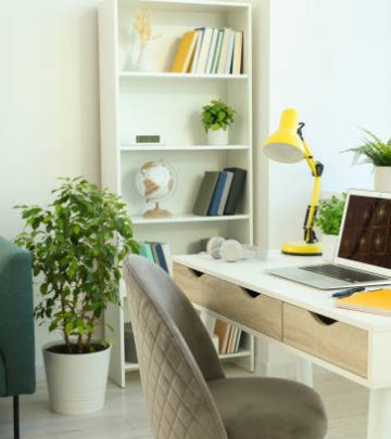 Cozy workspace with modern laptop on white wooden desk and comfortable chair at home