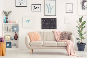 Elegant sofa, white shelf with decorations and posters on the wall in a living room interior