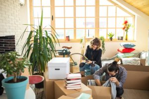 Young cheerful Couple packing cardboard boxes together during moving house